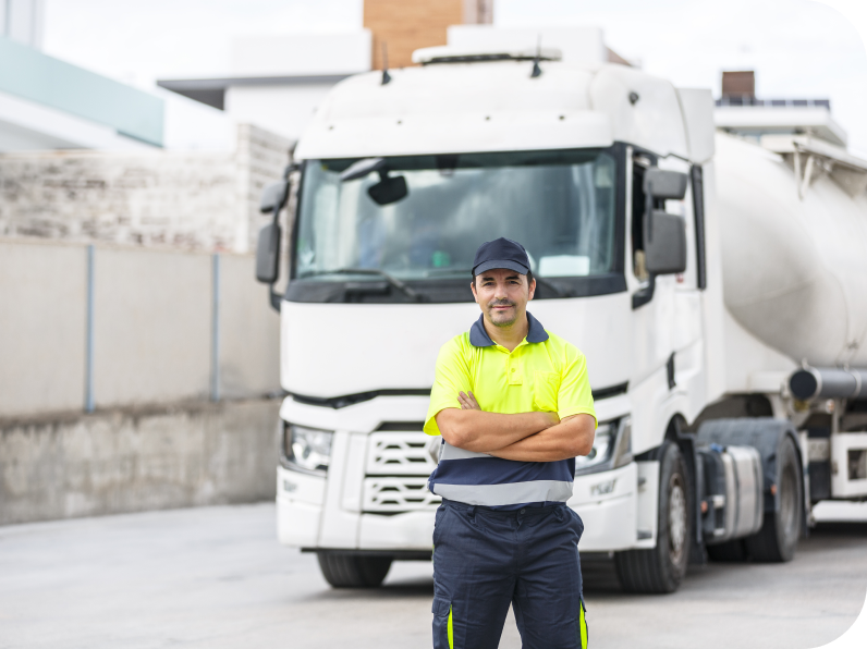 Truck driver in a high-visibility uniform standing confidently with arms crossed in front of a large commercial vehicle.