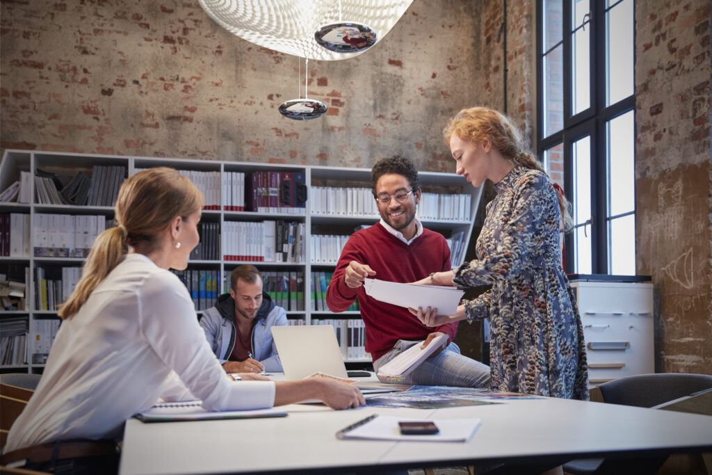 Colleagues collaborating around a table in a creative, modern office setting.