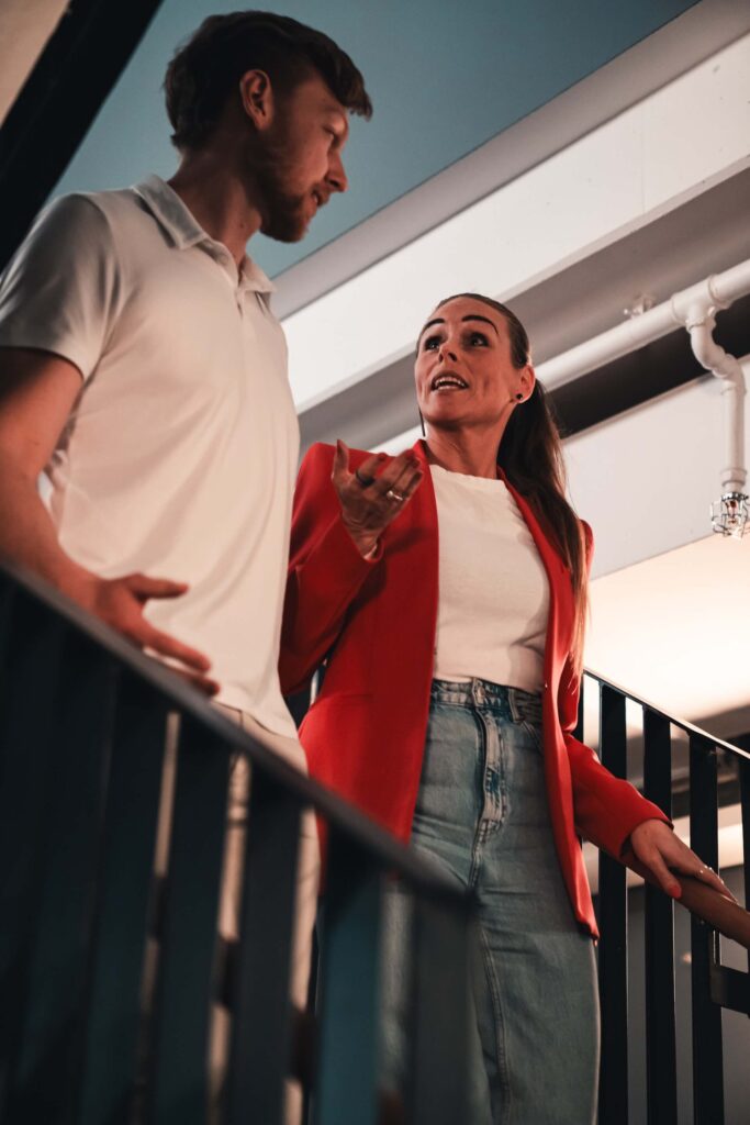 Two colleagues walking down a staircase while discussing something in a relaxed office setting.